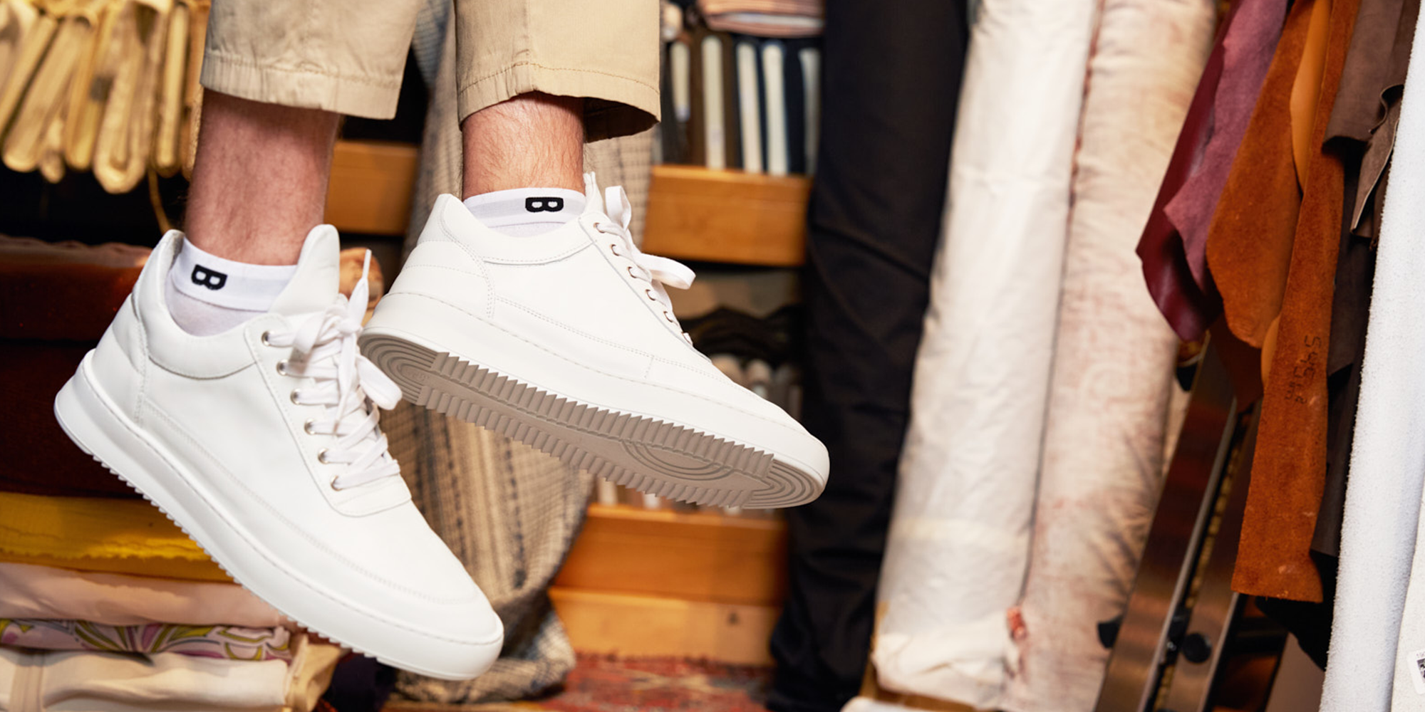 Close-up van witte plan-B origin sneakersok gedragen bij volledig witte sneakers