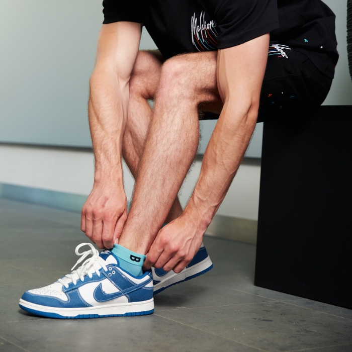 Laurens de Vries straalt in zijn effen blauwe Plug & Play sokken, gecombineerd met blauwe Nike Dunk Low sneakers.